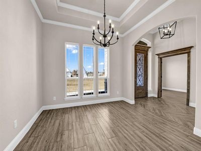 Foyer entrance featuring light hardwood / wood-style floors, an inviting chandelier, a tray ceiling, and crown molding