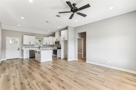 Kitchen featuring light hardwood / wood-style flooring, a center island, ceiling fan, appliances with stainless steel finishes, and white cabinets