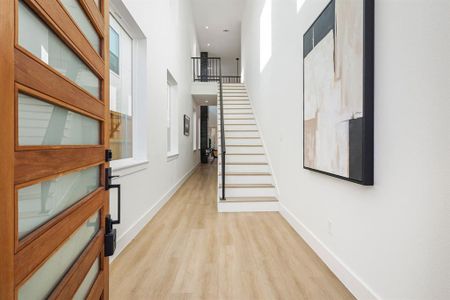 Hall with a towering ceiling and light hardwood / wood-style flooring