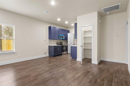 Kitchen featuring dark wood-type flooring, blue cabinets, decorative backsplash, and electric range