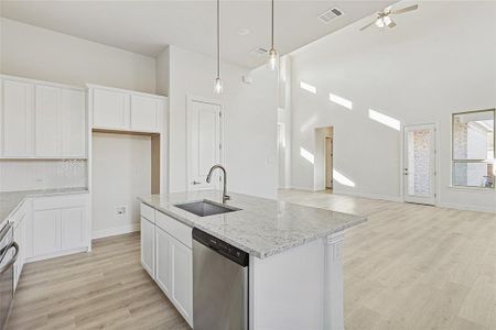 Kitchen with stainless steel dishwasher, white cabinets, and a kitchen island with sink