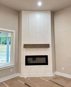 Electric Fireplace with a Modern White Surround Accent Wall and a Wooden Beam Mantel *Paper covering the Floor*