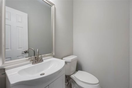 This photo shows a compact bathroom with a modern white sink, sleek faucet, and a large mirror above. The space includes a toilet and has neutral-colored walls, providing a clean and simple look.