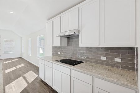 Kitchen featuring white cabinets, black electric stovetop, dark hardwood / wood-style flooring, and light stone counters