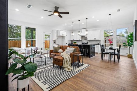 Living room featuring light hardwood / wood-style flooring, sink, ceiling fan with notable chandelier, and a wealth of natural light