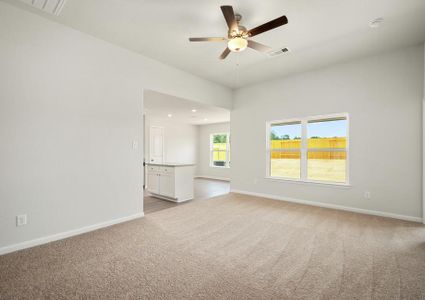 The spacious family room has carpet and a ceiling fan.