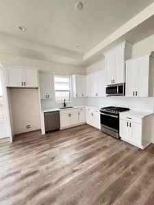 A tidy kitchen adorned with white cabinetry and warm hardwood flooring, creating a fresh and welcoming environment.