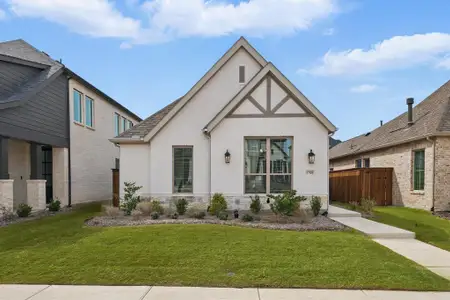 English style home featuring brick siding, a front lawn, and fence