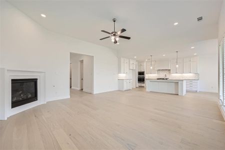 Unfurnished living room with ceiling fan, sink, and light wood-type flooring