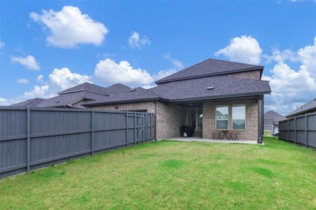 Rear view of property featuring a patio area, brick siding, a fenced backyard, a yard, and a shingled roof