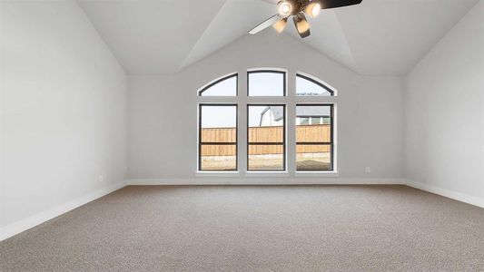 Empty room with vaulted ceiling, carpet flooring, and ceiling fan