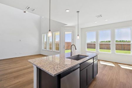 Kitchen with dishwasher, a kitchen island with sink, light hardwood / wood-style floors, sink, and light stone counters