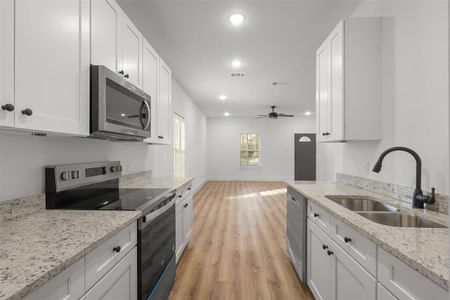 Kitchen with sink, white cabinetry, and appliances with stainless steel finishes