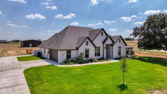 View of front of property featuring a garage and a front lawn with sprinkler system