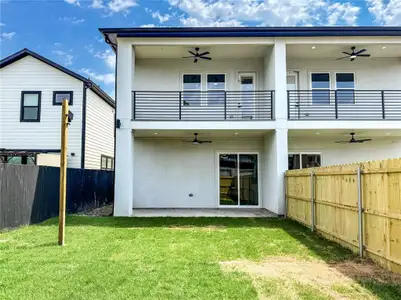 Back of house featuring a ceiling fan, a balcony, and stucco siding Back of house featuring a ceiling fan, a balcony, and stucco siding
