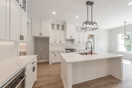 Kitchen with a kitchen island with sink, light hardwood / wood-style floors, backsplash, stainless steel appliances, and sink