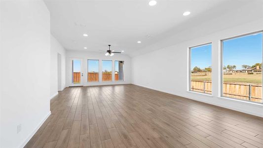 Unfurnished living room featuring hardwood / wood-style floors, ceiling fan, and a wealth of natural light