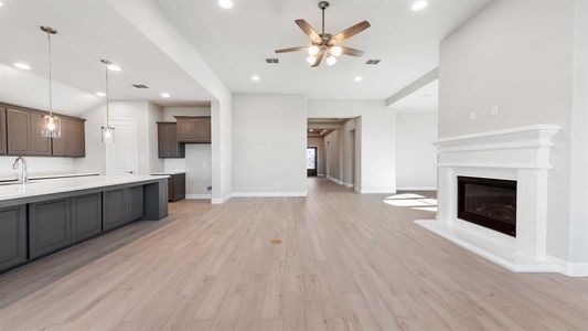 Unfurnished living room featuring ceiling fan, sink, and light hardwood / wood-style floors