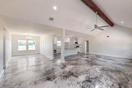 Unfurnished living room with ceiling fan with notable chandelier and vaulted ceiling with beams