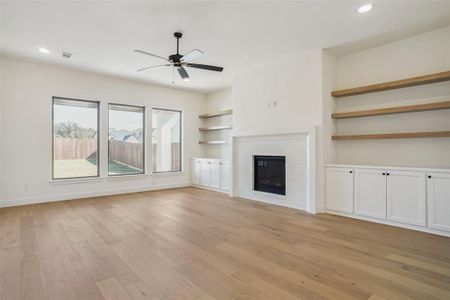 Unfurnished living room with ceiling fan, light wood-type flooring, and a brick fireplace