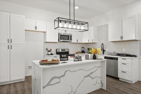 Kitchen with white cabinetry, a center island, hanging light fixtures, appliances with stainless steel finishes, and dark hardwood / wood-style floors