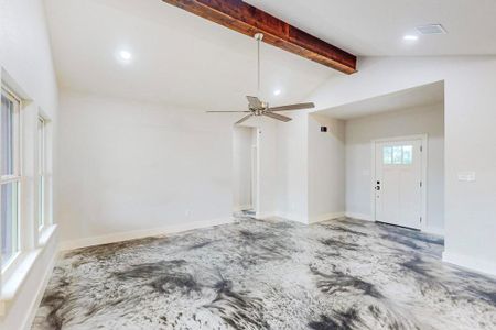 Unfurnished living room featuring ceiling fan and lofted ceiling with beams