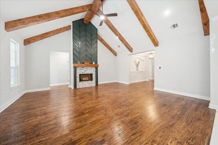 Unfurnished living room with dark hardwood / wood-style flooring, a fireplace, high vaulted ceiling, and beamed ceiling