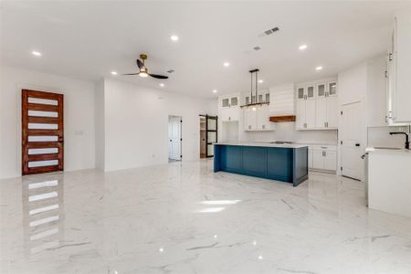 Kitchen with pendant lighting, a center island, premium range hood, ceiling fan, and white cabinetry