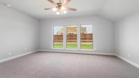 Carpeted spare room featuring ceiling fan and vaulted ceiling