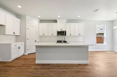 Kitchen featuring white cabinetry, sink, and an island with sink