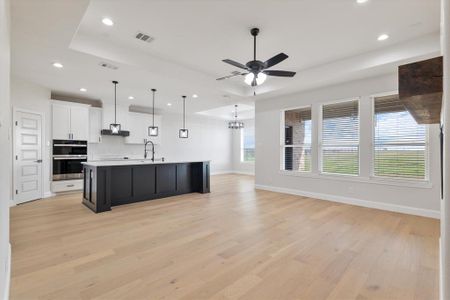 Kitchen with visible vents, a spacious island, open floor plan, a tray ceiling, and white cabinetry