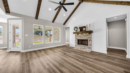 Living room with ceiling fan, beamed ceiling, high vaulted ceiling, LVP flooring, and a large fireplace