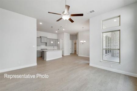 Unfurnished living room with sink, light hardwood / wood-style floors, and ceiling fan with notable chandelier