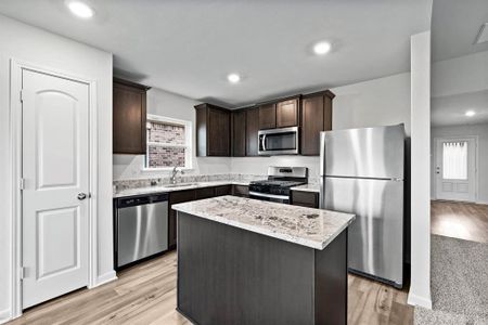 Kitchen featuring light wood-type flooring, a center island, stainless steel appliances, dark brown cabinetry, and sink