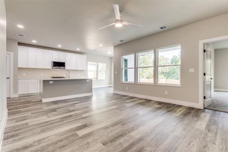 Kitchen featuring white cabinetry, light hardwood / wood-style flooring, sink, an island with sink, and ceiling fan