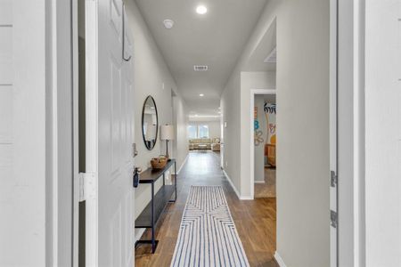 Inviting entry hallway with wood-like vinyl flooring and modern accents leads to a bright, open living area