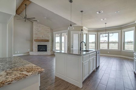 Kitchen featuring dark hardwood / wood-style floors, a fireplace, an island with sink, sink, and white cabinetry