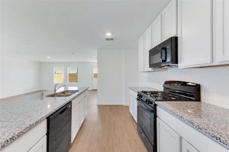 Kitchen featuring light wood-type flooring, black appliances, sink, and white cabinets