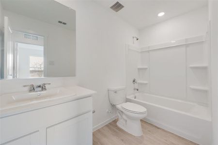 Full bathroom with toilet, tub / shower combination, hardwood / wood-style flooring, and vanity