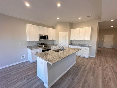 Kitchen featuring wood-type flooring, stainless steel appliances, white cabinetry, and sink