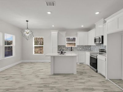 Kitchen featuring white cabinets, appliances with stainless steel finishes, decorative light fixtures, a kitchen island, and a chandelier