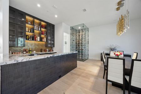 Bar featuring tasteful backsplash, light hardwood / wood-style flooring, and light stone counters