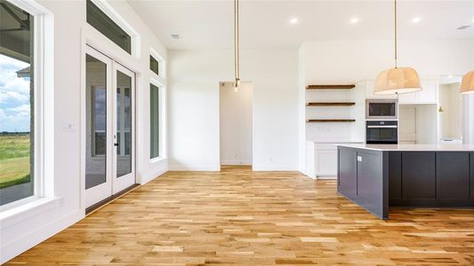 Kitchen featuring hanging light fixtures, white cabinets, black appliances, and light hardwood / wood-style flooring