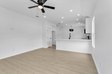 Unfurnished living room featuring ceiling fan, sink, and light hardwood / wood-style flooring