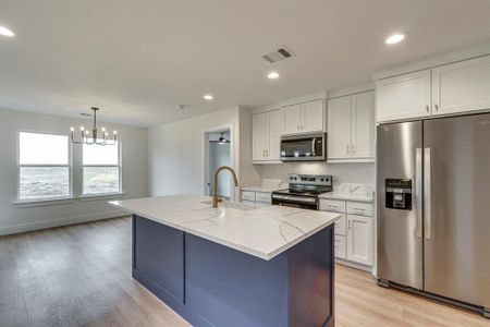 Kitchen featuring light stone counters, visible vents, white cabinetry, appliances with stainless steel finishes, and light wood-type flooring