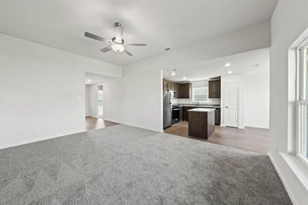 Unfurnished living room featuring dark carpet, a ceiling fan, and baseboards