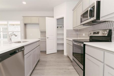 Kitchen featuring stainless steel appliances, white cabinets, tasteful backsplash, sink, and light hardwood / wood-style flooring