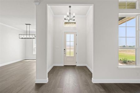 Foyer entrance featuring a notable chandelier, crown molding, and dark hardwood / wood-style flooring