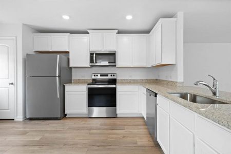 Kitchen includes granite countertops, luxury vinyl plank flooring, 36” upper cabinets with crown molding, a full suite of stainless-steel Whirlpool appliances – including refrigerator with ice maker, recessed lighting, and a large single basin sink.