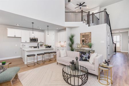 Living room with a high ceiling, light hardwood / wood-style flooring, ceiling fan, and sink